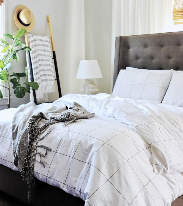 Bed made up in windowpane sheets.  Everything in the room is white and grey