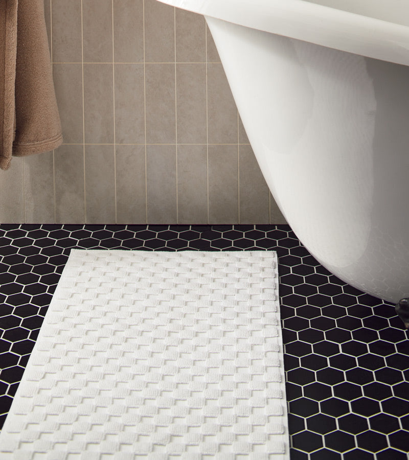 Blue bath checkered rugs draped in front of a claw foot tub
