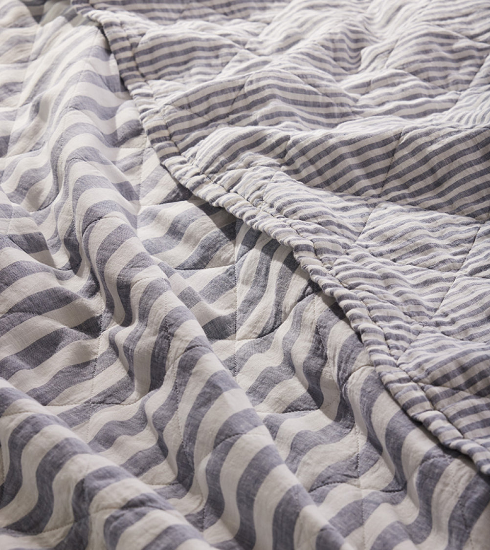 A striped reversible quilt, folded over itself, revealing two different stripe patterns.
