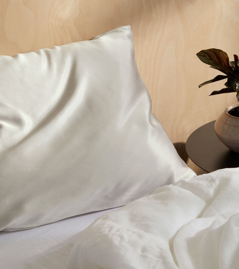 Overhead shot of a bed with 4 silk pillowcases, a silk scrunchie, and a silk eyemask