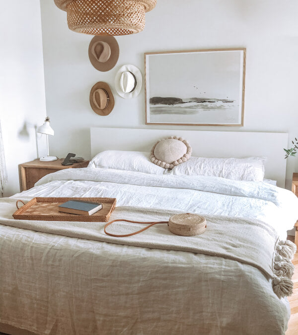 Bed made up in rumpled white linen sheets.  Everything in the room is beige.