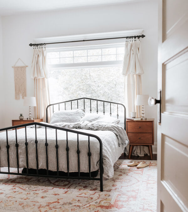 Bed of striped linen sheets on a black metal bedframe.