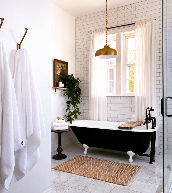 All white bathroom with a black clawfoot tub with white towels
