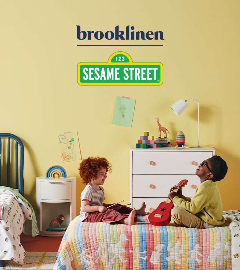 Kids having a jam sesh on a bed made up with Sesame Street sheets.