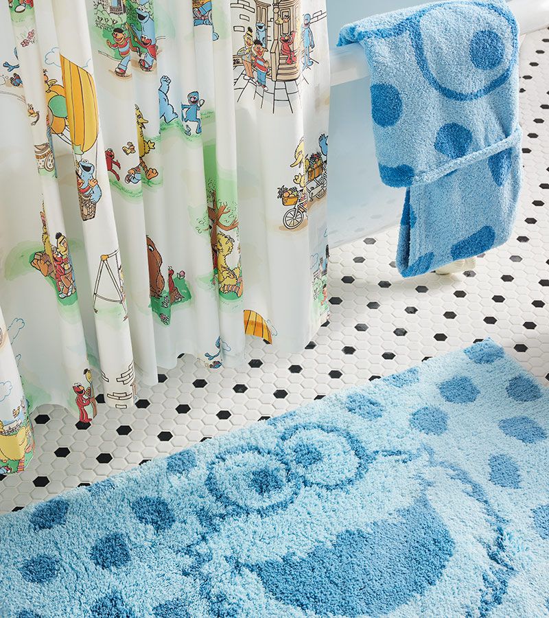 A bathroom decked out in the Cookie Monster bath mat and Sesame Street shower curtain.