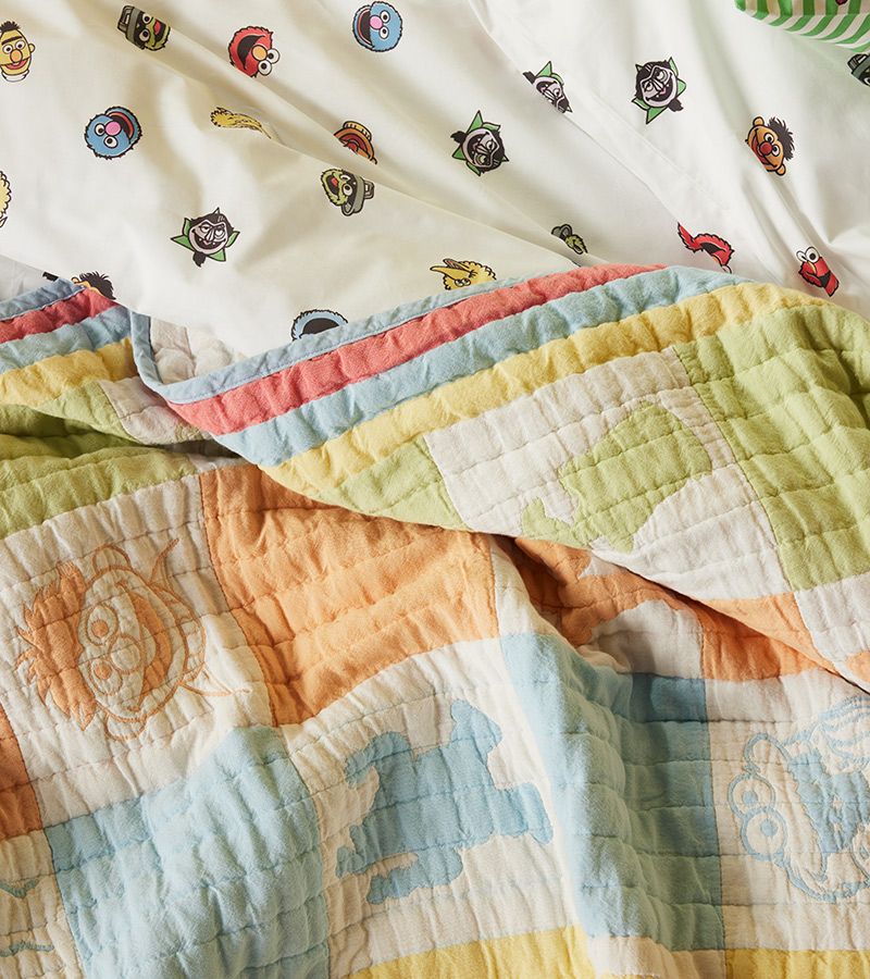 A bed made up with our whimsical Sesame Street quilt.