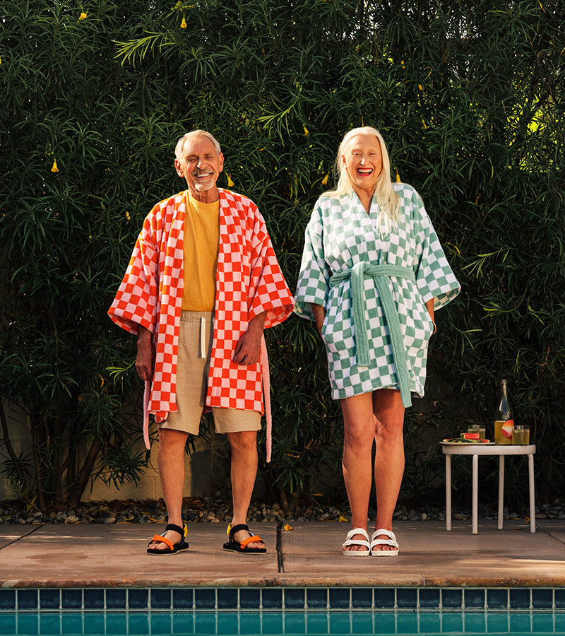A sun-dappled couple stands happily in their Checkerboard Robes, poolside.