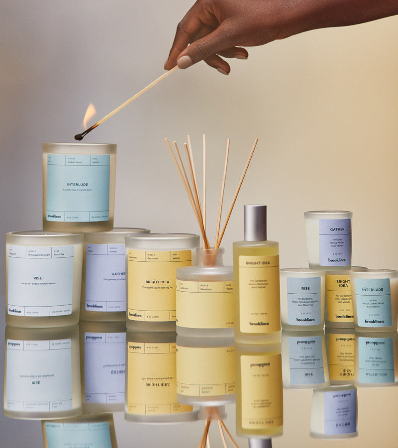 Full set of home fragrance, with a hand lighting one of the candles