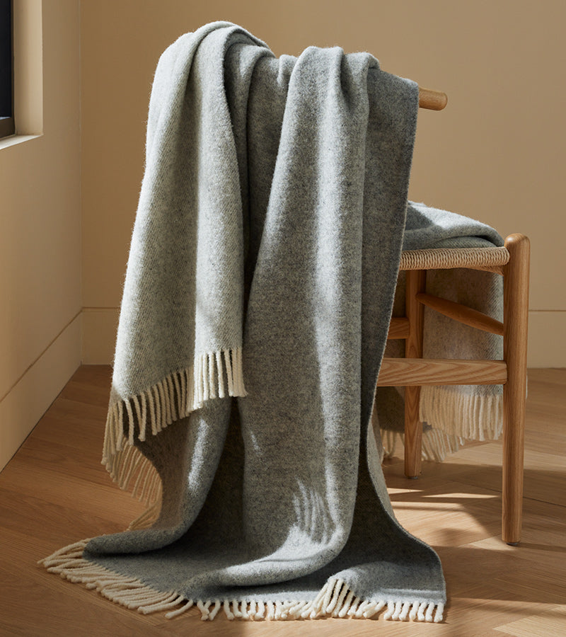 A wool throw draped comfortably over a wishbone chair.