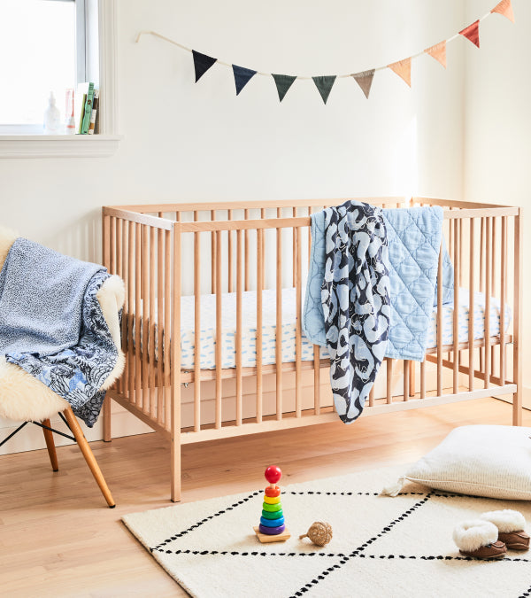 A wood crib done up in all items from a baby bundle