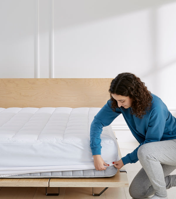Woman putting a topper on a bed