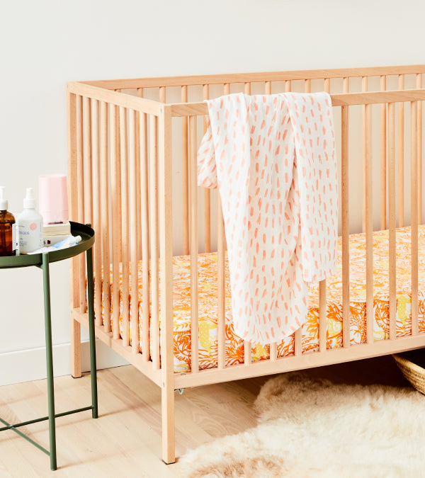 Wood crib done up in a peach version of the crib set