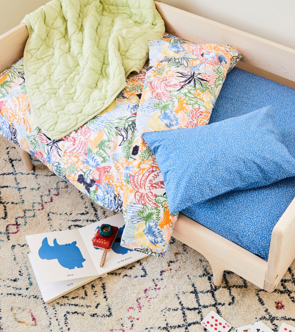 A toddler bed made up in blues and greens